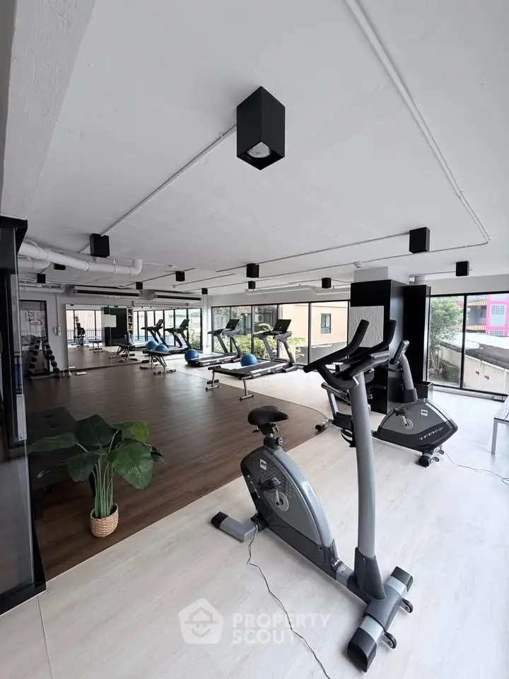 Modern gym with exercise equipment and large windows offering a bright and airy workout space.