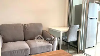 Cozy living area with modern sofa and compact dining space near kitchen.