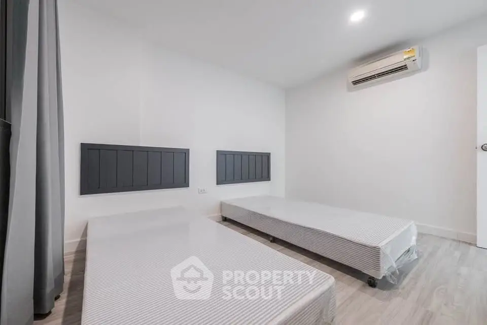 Spacious bedroom with twin beds and modern air conditioning unit, perfect for comfortable living.
