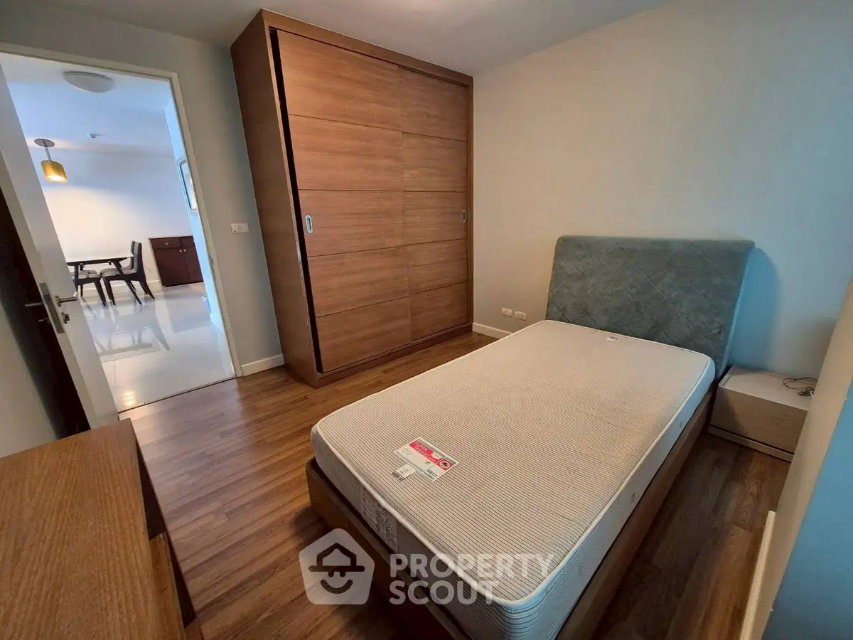 Cozy bedroom with wooden flooring and built-in wardrobe, perfect for modern living.