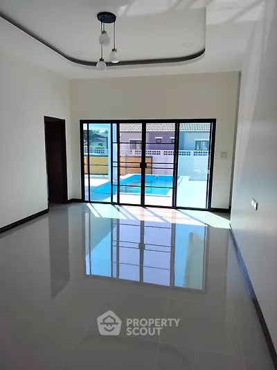 Spacious living room with large windows and pool view, perfect for modern living.