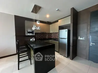 Modern kitchen with sleek design, featuring a breakfast bar, stainless steel appliances, and stylish lighting.