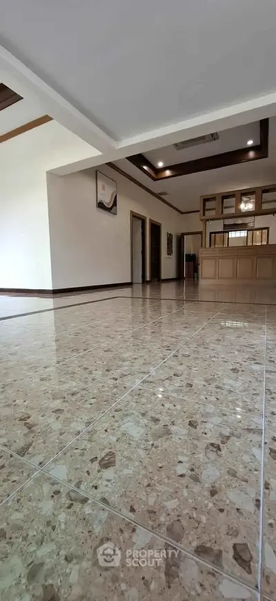 Spacious living room with elegant marble flooring and modern ceiling design.