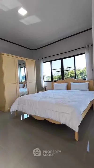 Spacious bedroom with large windows and modern furnishings, offering a serene and comfortable living space.