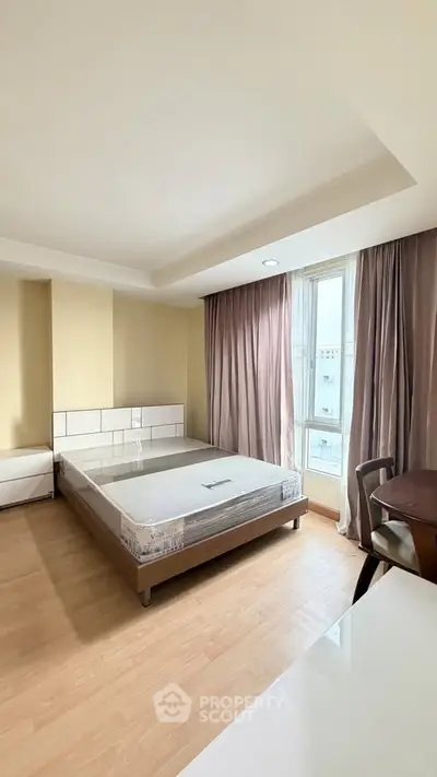 Spacious bedroom with natural light and modern furnishings in a stylish apartment.