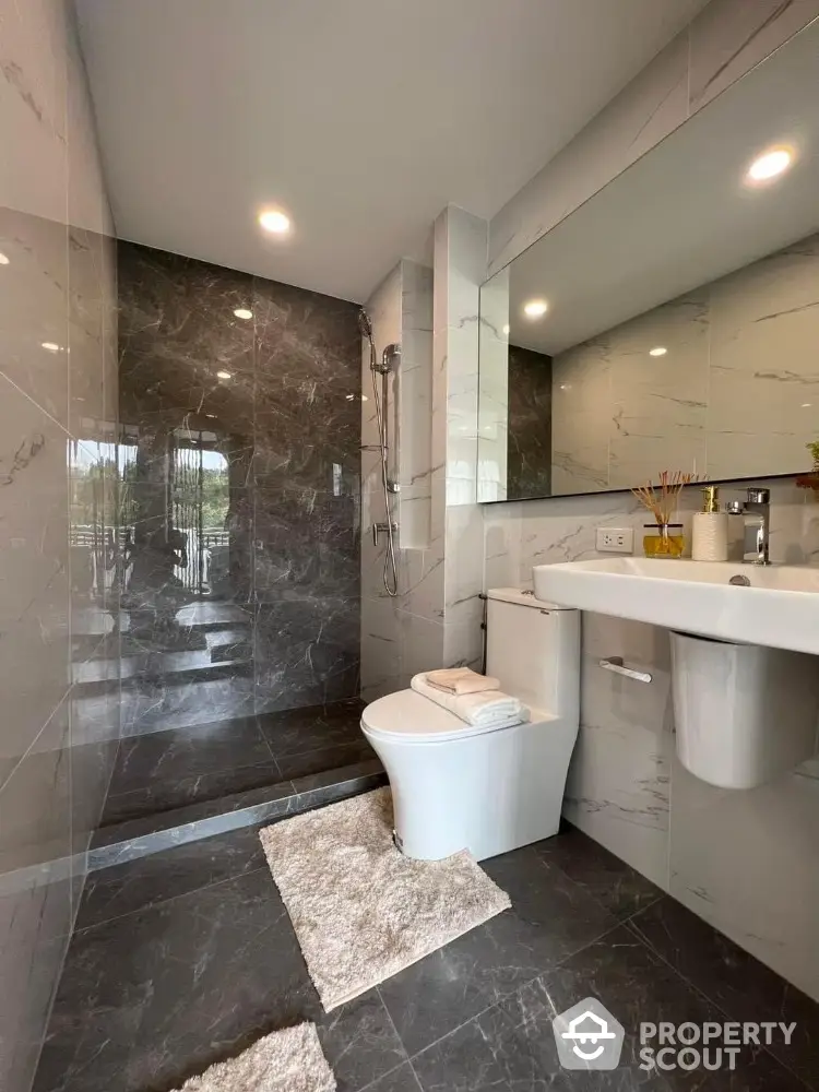 Modern bathroom with sleek design, featuring a walk-in shower and elegant marble tiles.