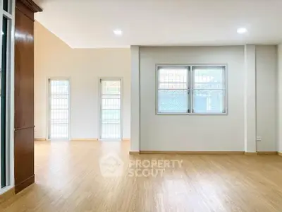 Spacious modern living room with wooden flooring and large windows for natural light.