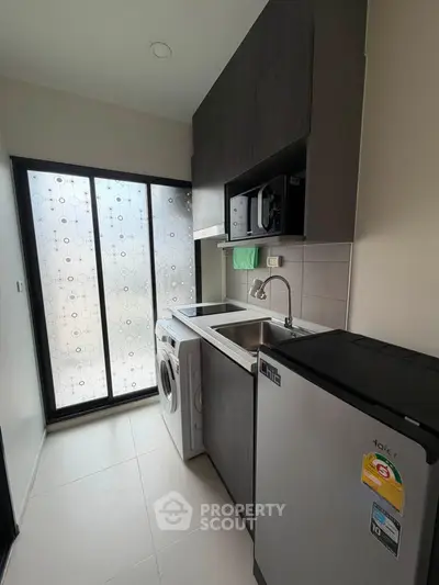 Modern kitchen with sleek appliances and ample natural light through frosted glass doors.