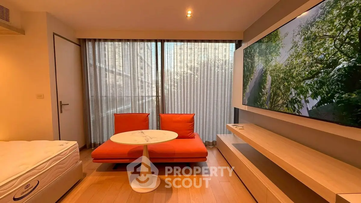 Modern living room with stylish furniture and large TV, featuring floor-to-ceiling windows and natural light.