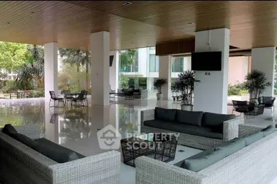 Expansive and elegant open-plan living space with high ceilings, sleek furniture, and a seamless transition to the lush outdoor garden.