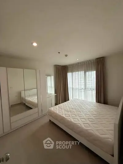 Spacious bedroom with large windows and modern furnishings in a stylish apartment.