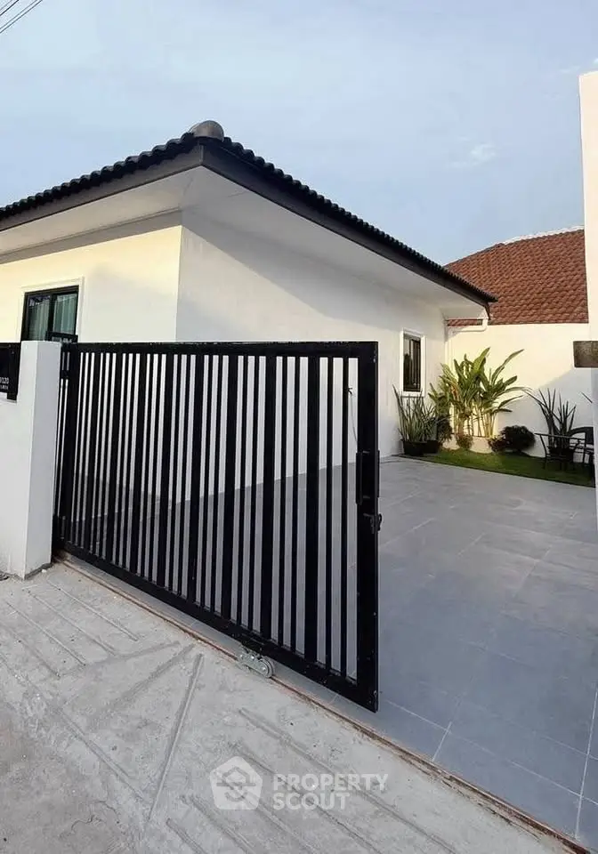 Modern single-story home with sleek black gate and minimalist landscaping.