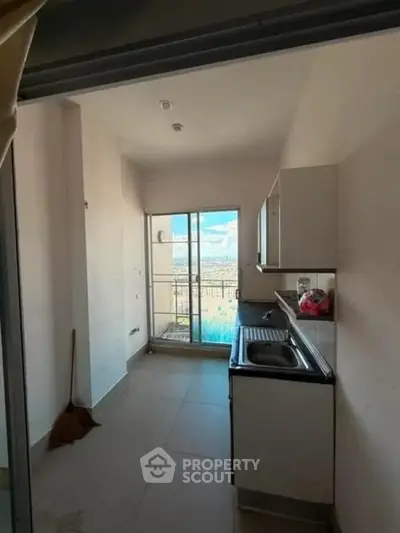 Modern kitchen with balcony view, sleek cabinets, and ample natural light.