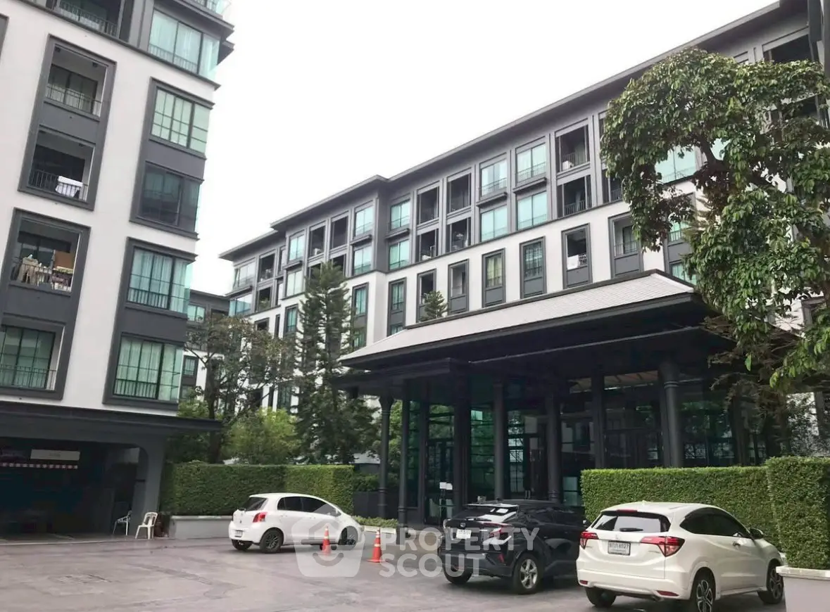 Modern apartment building exterior with parking area and lush greenery