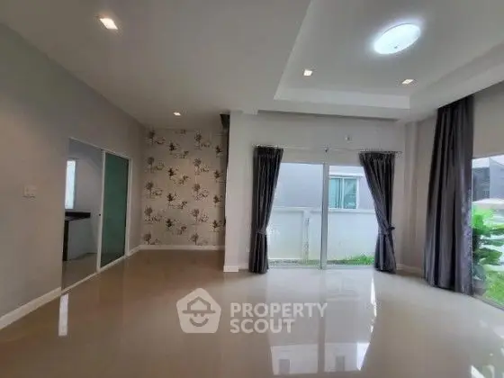 Spacious modern living room with large windows and elegant curtains, perfect for natural light.
