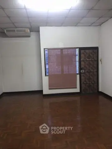 Spacious empty room with parquet flooring and window blinds