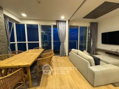 Spacious living room with panoramic windows and elegant decor, offering stunning night views.
