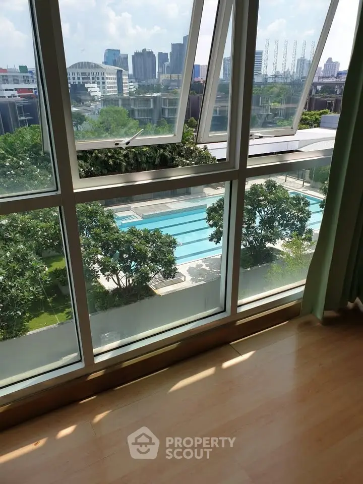 Stunning pool view from modern apartment window with cityscape backdrop