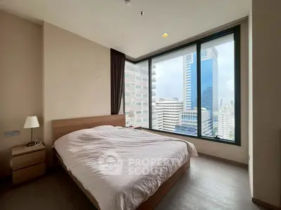 Spacious bedroom with large windows offering stunning city views in modern apartment.