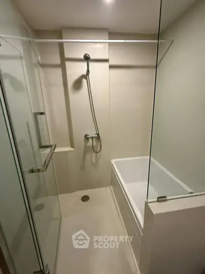 Modern bathroom with glass shower and bathtub in sleek minimalist design.