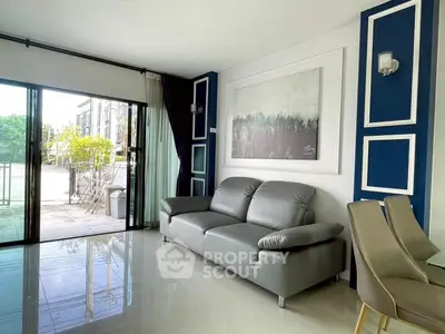 Modern living room with sleek gray sofa and elegant decor, featuring large windows for natural light.
