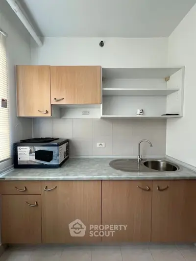 Modern kitchen with sleek cabinetry and stainless steel sink, featuring a microwave on the countertop.
