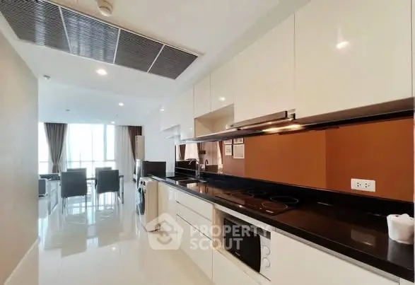 Modern kitchen with sleek cabinets and open layout leading to dining area