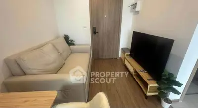 Cozy living room with modern sofa and flat-screen TV, perfect for relaxation.