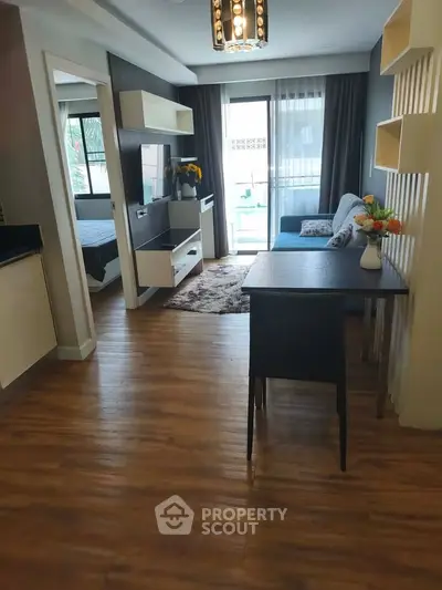 Modern living room with stylish decor and wooden flooring, featuring a cozy dining area and natural light.