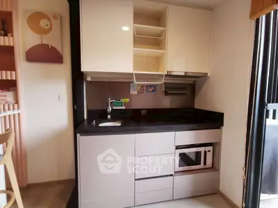 Modern compact kitchen with sleek cabinetry and built-in microwave