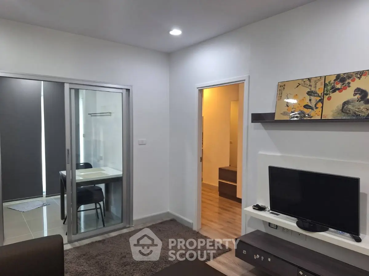 Modern living room with sleek design and sliding glass doors leading to a dining area.