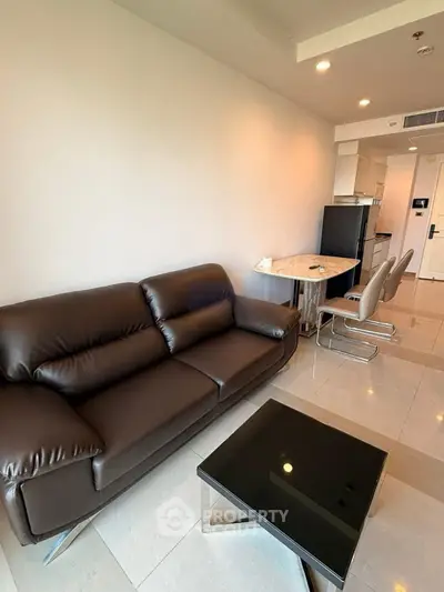 Modern living room with sleek leather sofa and stylish dining area in open layout apartment.