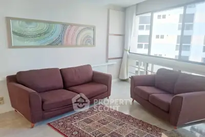 Spacious living room with modern sofas and large window offering natural light.