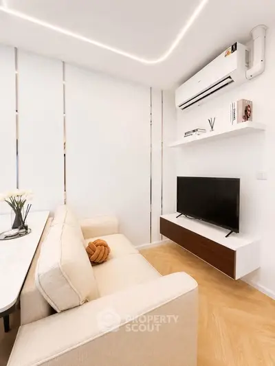 Modern living room with sleek design, featuring a cozy beige sofa, wall-mounted TV, and stylish shelving.