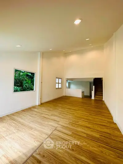 Spacious open-plan living room with wooden flooring and natural light