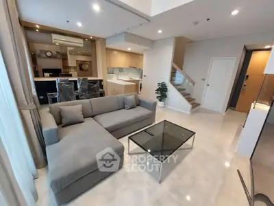 Modern living room with open kitchen and stylish gray sofa in a spacious apartment.
