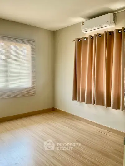 Spacious empty room with wooden flooring and air conditioning, ideal for customization.