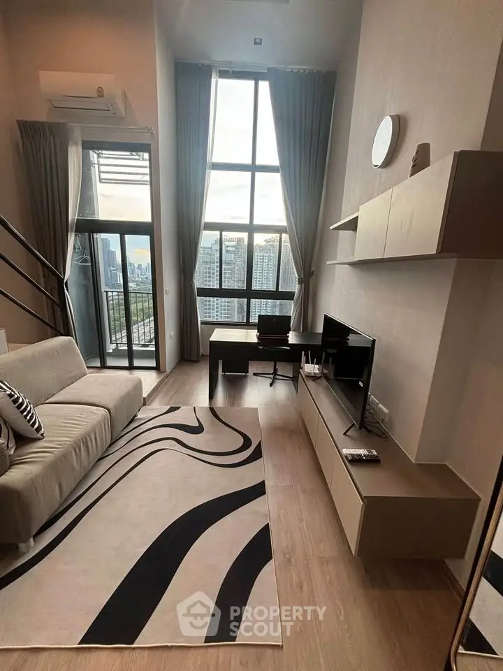 Modern living room with high ceilings and large windows offering city views.