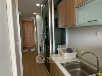 Compact kitchen with wooden cabinets and glass sliding doors in modern apartment