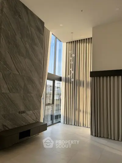 Luxurious high-ceiling living room with floor-to-ceiling windows and elegant drapery