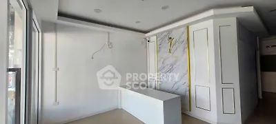 Modern commercial space with sleek white interior and marble accent wall, ideal for business setup.