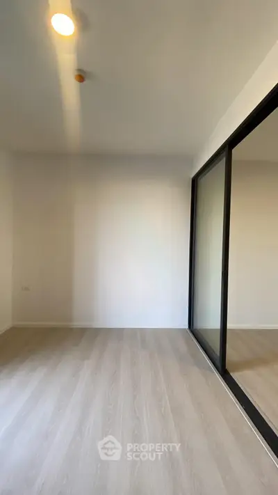 Spacious bedroom with mirrored sliding doors and elegant wooden flooring.