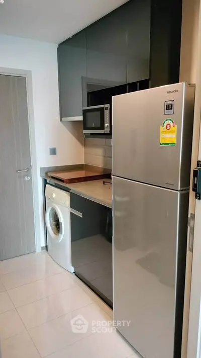 Modern compact kitchen with sleek appliances and washing machine in stylish apartment.