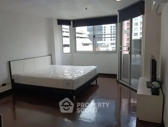 Spacious bedroom with large windows and balcony access in modern apartment.