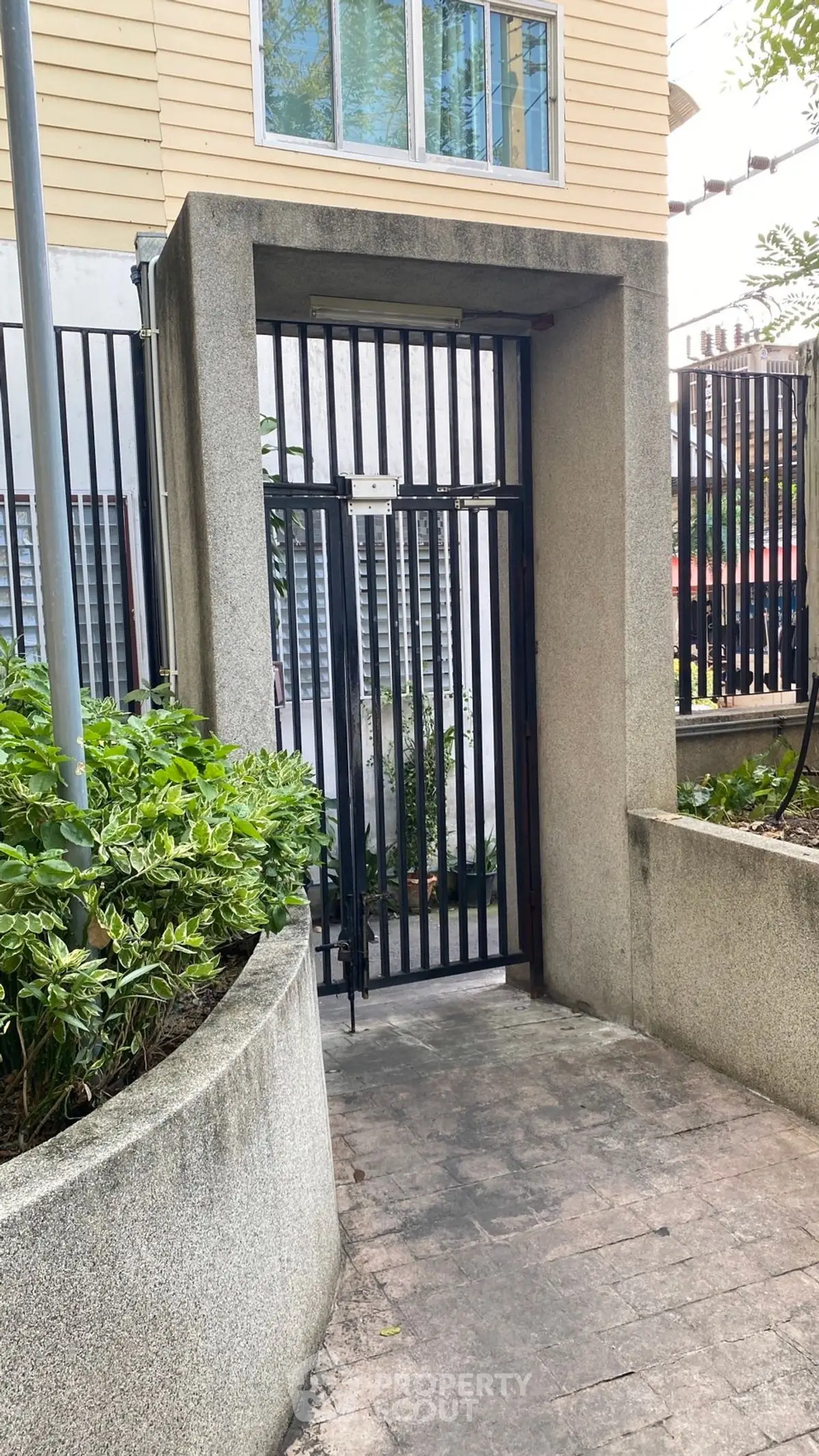 Secure gated entrance with modern design and lush greenery