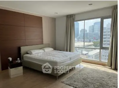 Spacious bedroom with large window offering stunning city views in modern apartment.