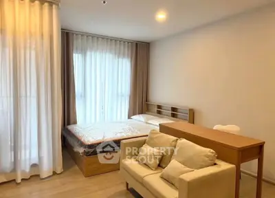 Modern studio apartment with cozy bed and stylish sofa in bright, airy space.