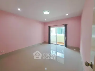Spacious empty room with pink walls and large window for natural light