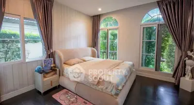 Spacious bedroom with elegant decor and large windows offering lush garden views.