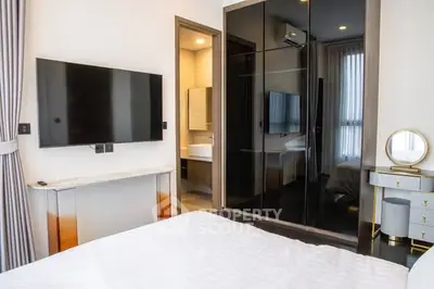 Modern bedroom with sleek black wardrobe and wall-mounted TV